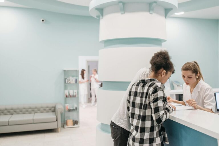 Healthcare professionals assisting at a modern clinic reception desk.